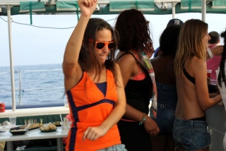 chica con una camiseta naranja a juego con las gafas bailando en un barco